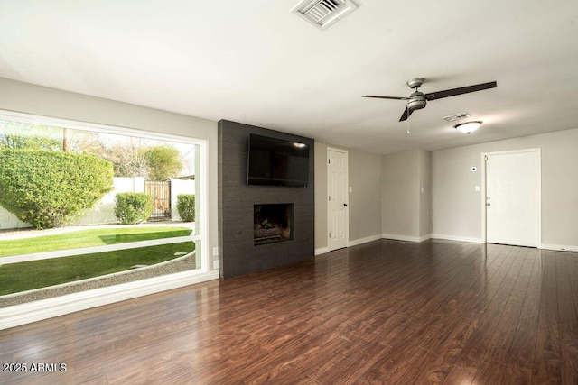 unfurnished living room with ceiling fan, dark hardwood / wood-style flooring, and a large fireplace