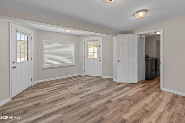entrance foyer with washing machine and dryer, light wood-style floors, and baseboards