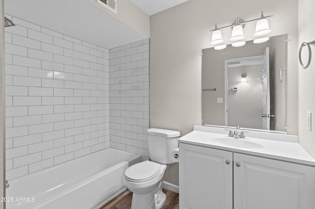 bathroom with toilet, vanity, wood finished floors, visible vents, and a textured wall