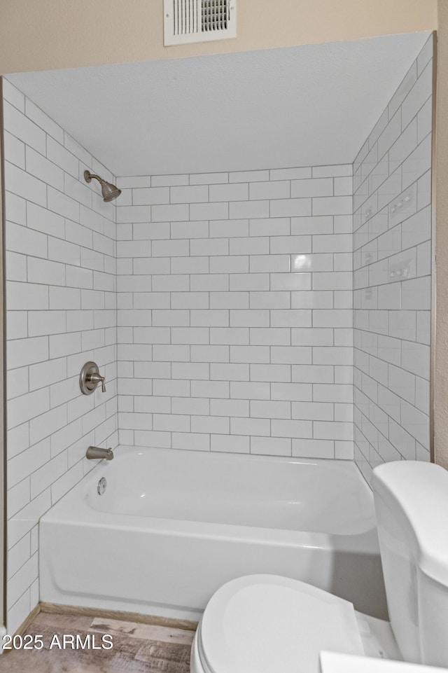 bathroom with shower / bathing tub combination, visible vents, and toilet