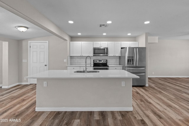 kitchen with stainless steel appliances, a sink, light wood finished floors, visible vents, and white cabinets