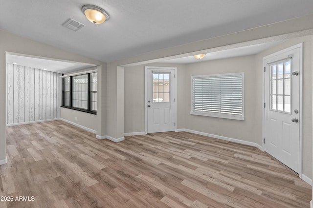 foyer entrance featuring light wood finished floors, visible vents, and a healthy amount of sunlight