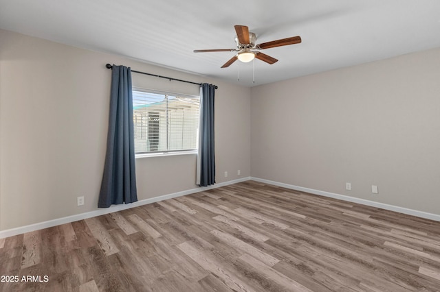 spare room with baseboards, wood finished floors, and ceiling fan