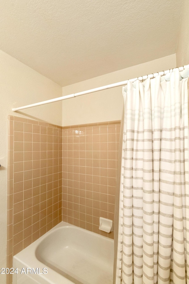 bathroom with shower / tub combo and a textured ceiling