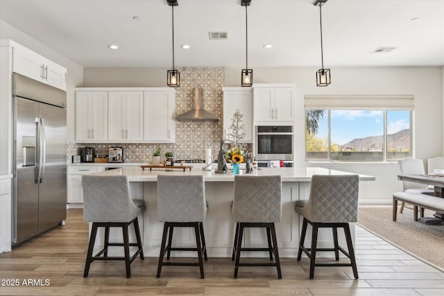 8396 E Granite Pass Rd, Scottsdale, AZ 85266 - kitchen featuring appliances with stainless steel finishes, wall chimney range hood, light countertops, decorative backsplash, and white cabinetry