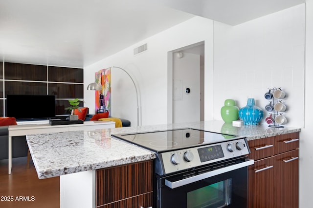 kitchen featuring stainless steel electric stove, light stone countertops, and modern cabinets