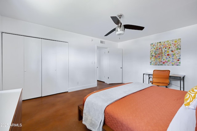 bedroom with a closet, finished concrete flooring, ceiling fan, and baseboards