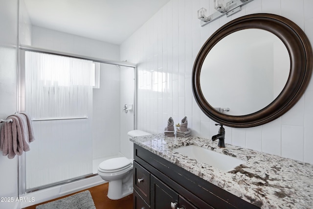 full bathroom featuring a shower stall, toilet, vanity, and tile walls