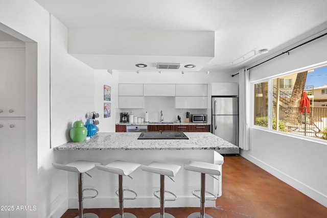 kitchen with stainless steel appliances, a sink, baseboards, a peninsula, and a breakfast bar area