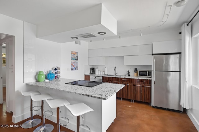 kitchen featuring appliances with stainless steel finishes, a sink, modern cabinets, and a breakfast bar
