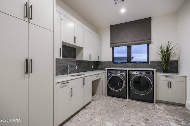 laundry room with cabinets, sink, and washing machine and dryer