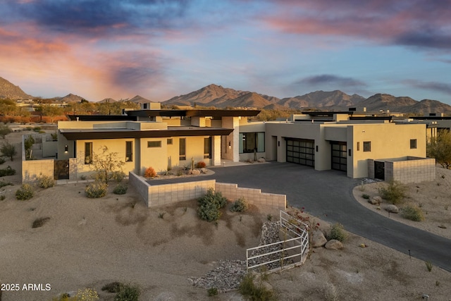 back house at dusk featuring a garage and a mountain view