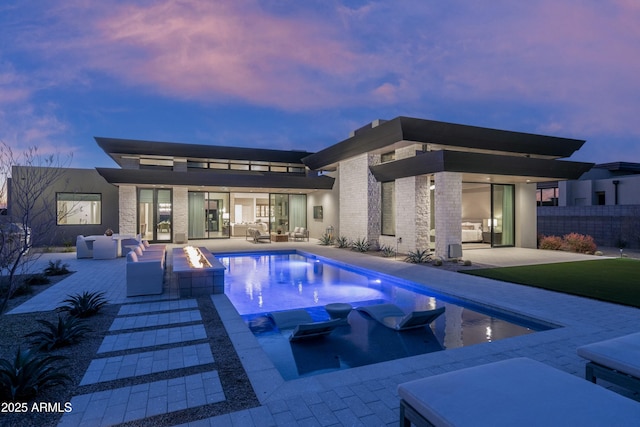 back house at dusk with a patio area and an outdoor fire pit