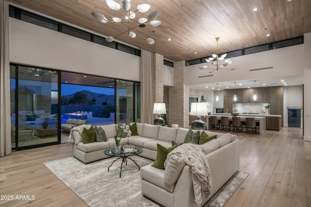 living room featuring a notable chandelier, light hardwood / wood-style flooring, wooden ceiling, and a high ceiling