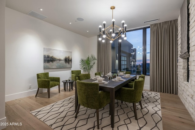 dining area featuring a wall of windows, an inviting chandelier, and light hardwood / wood-style flooring