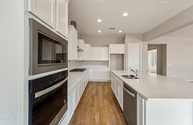 kitchen featuring sink, white cabinets, stainless steel appliances, and a center island with sink