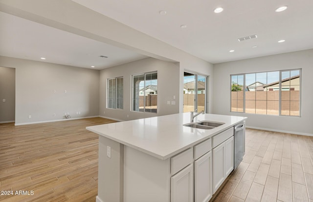 kitchen with stainless steel dishwasher, sink, a center island with sink, light hardwood / wood-style floors, and white cabinetry