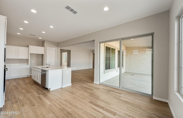 kitchen with sink, a center island with sink, light hardwood / wood-style flooring, dishwasher, and white cabinetry