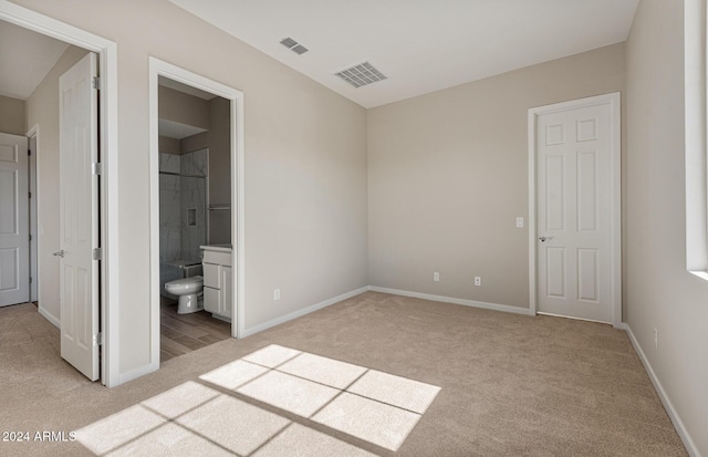 unfurnished bedroom with ensuite bathroom and light carpet