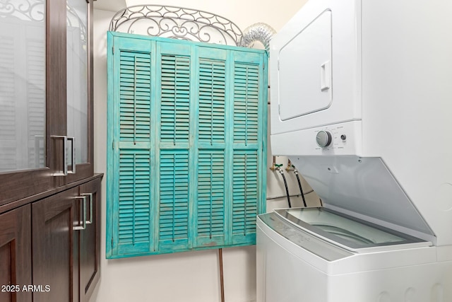 clothes washing area featuring cabinets and stacked washer / drying machine