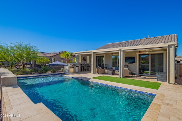 view of swimming pool with a patio, an outdoor living space, an outdoor kitchen, and ceiling fan