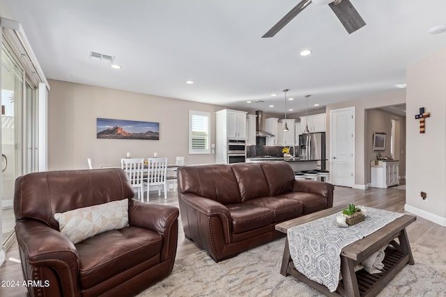 living room featuring ceiling fan and light hardwood / wood-style flooring