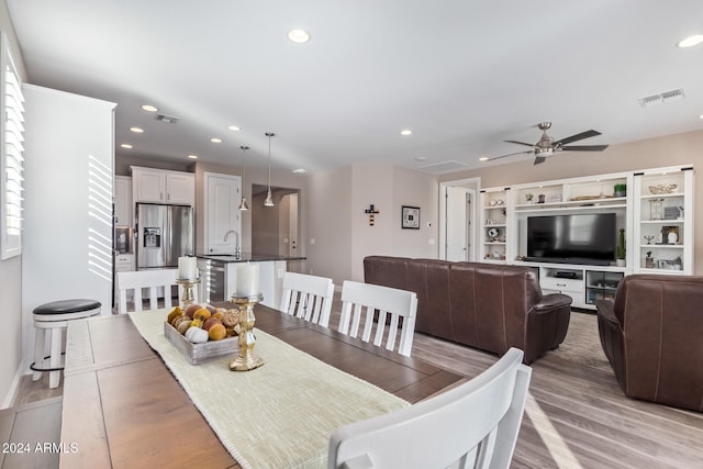 dining room with ceiling fan, sink, and light hardwood / wood-style floors