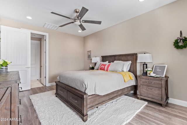 bedroom with ceiling fan, light hardwood / wood-style floors, and ensuite bath