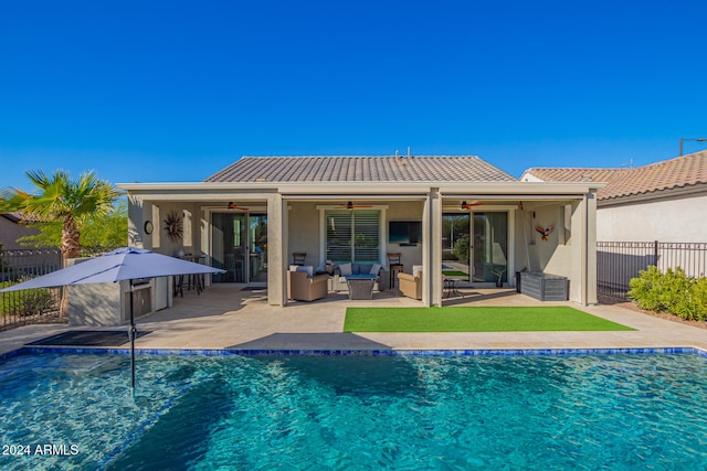 rear view of house with outdoor lounge area, a fenced in pool, ceiling fan, and a patio area