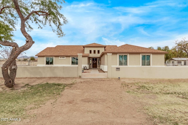 rear view of property with a fenced front yard and stucco siding