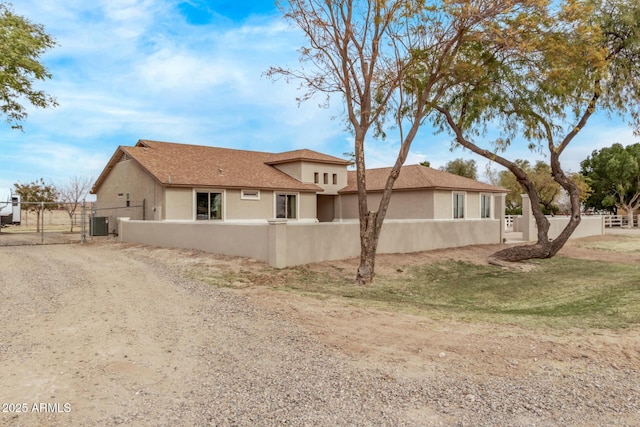 view of property exterior with a fenced front yard, a gate, and stucco siding