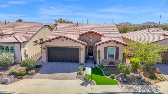 view of front of house with stucco siding, a tile roof, decorative driveway, a mountain view, and an attached garage