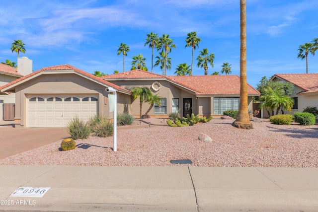 view of front facade featuring a tile roof, an attached garage, driveway, and stucco siding