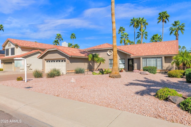 view of front facade with a tiled roof, an attached garage, driveway, and stucco siding