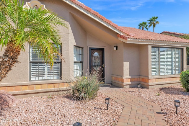 entrance to property with stucco siding and a tiled roof