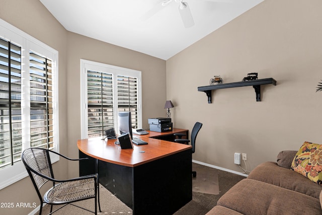 carpeted office space featuring baseboards, lofted ceiling, and a ceiling fan