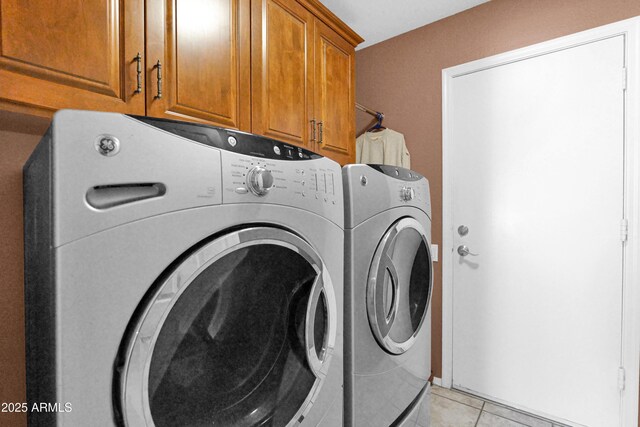 washroom featuring washing machine and dryer, light tile patterned floors, and cabinet space