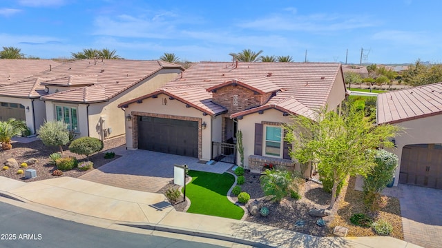 view of front of house featuring stucco siding, an attached garage, a tile roof, and decorative driveway