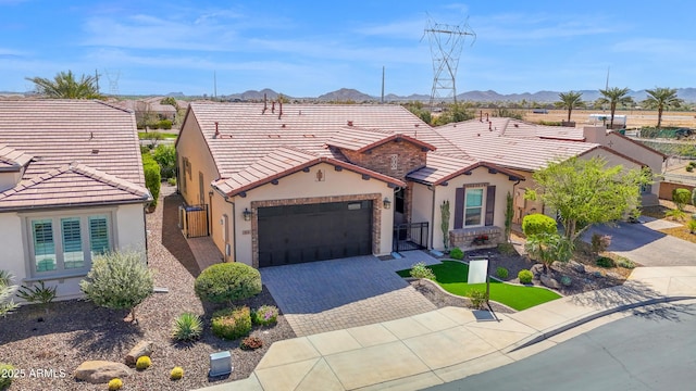 view of front facade featuring a mountain view, a tiled roof, decorative driveway, and a garage