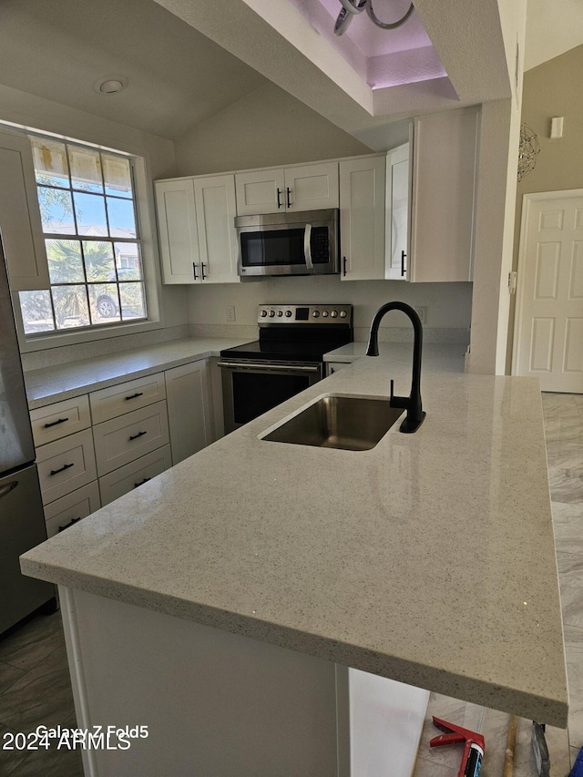 kitchen with kitchen peninsula, appliances with stainless steel finishes, white cabinetry, and sink