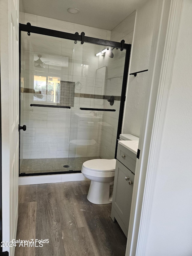 bathroom with vanity, toilet, wood-type flooring, and a shower with shower door