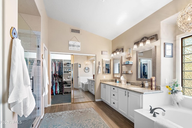 bathroom featuring lofted ceiling, vanity, and plus walk in shower