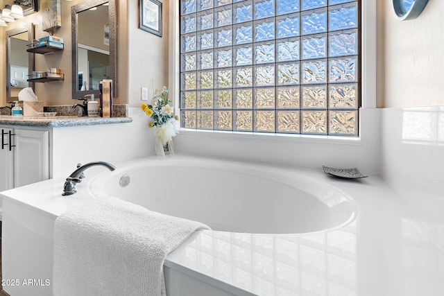 bathroom featuring vanity and tiled bath