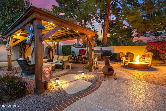 patio terrace at dusk featuring a gazebo and an outdoor living space with a fire pit