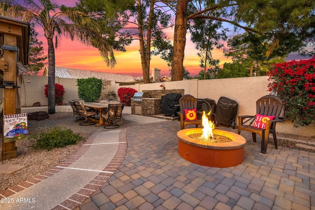 patio terrace at dusk with a grill, area for grilling, and a fire pit