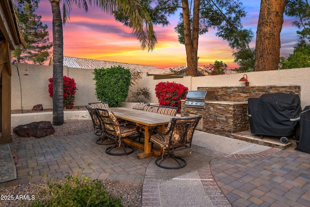 patio terrace at dusk with a grill and exterior kitchen