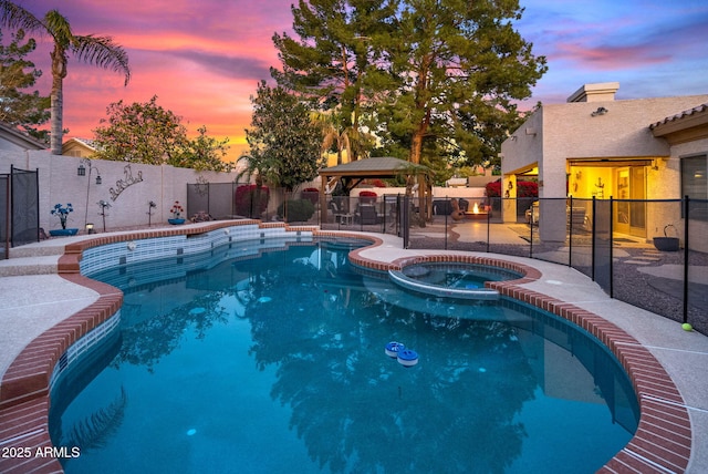 pool at dusk featuring a gazebo and an in ground hot tub