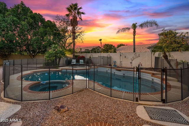 pool at dusk with an in ground hot tub