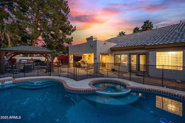 pool at dusk with a gazebo, a patio, and an in ground hot tub