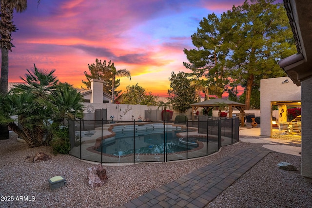 pool at dusk featuring a gazebo and a patio area